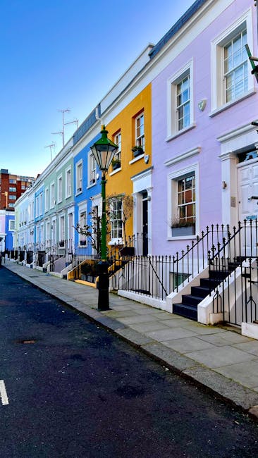 Two movers from Man and Van South Kensington are engaged in a furniture transport process, loading a large, dark green upholstered armchair into the rear of a white panel van with open rear doors. The